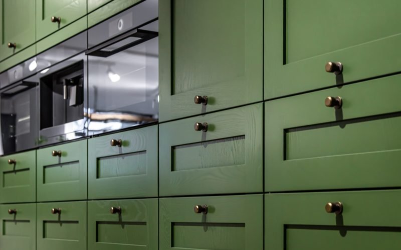Large green kitchen cabinet with many handles, close-up. Large green kitchen cabinet with many handles and a built-in oven, close-up.